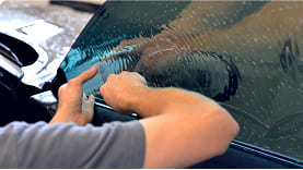 Accutint team member applying car window tint to a car window
