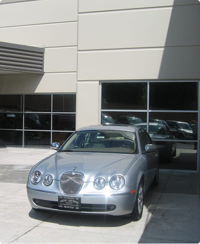 Silver Jaguar car parked outside of a building that has window tinting applied