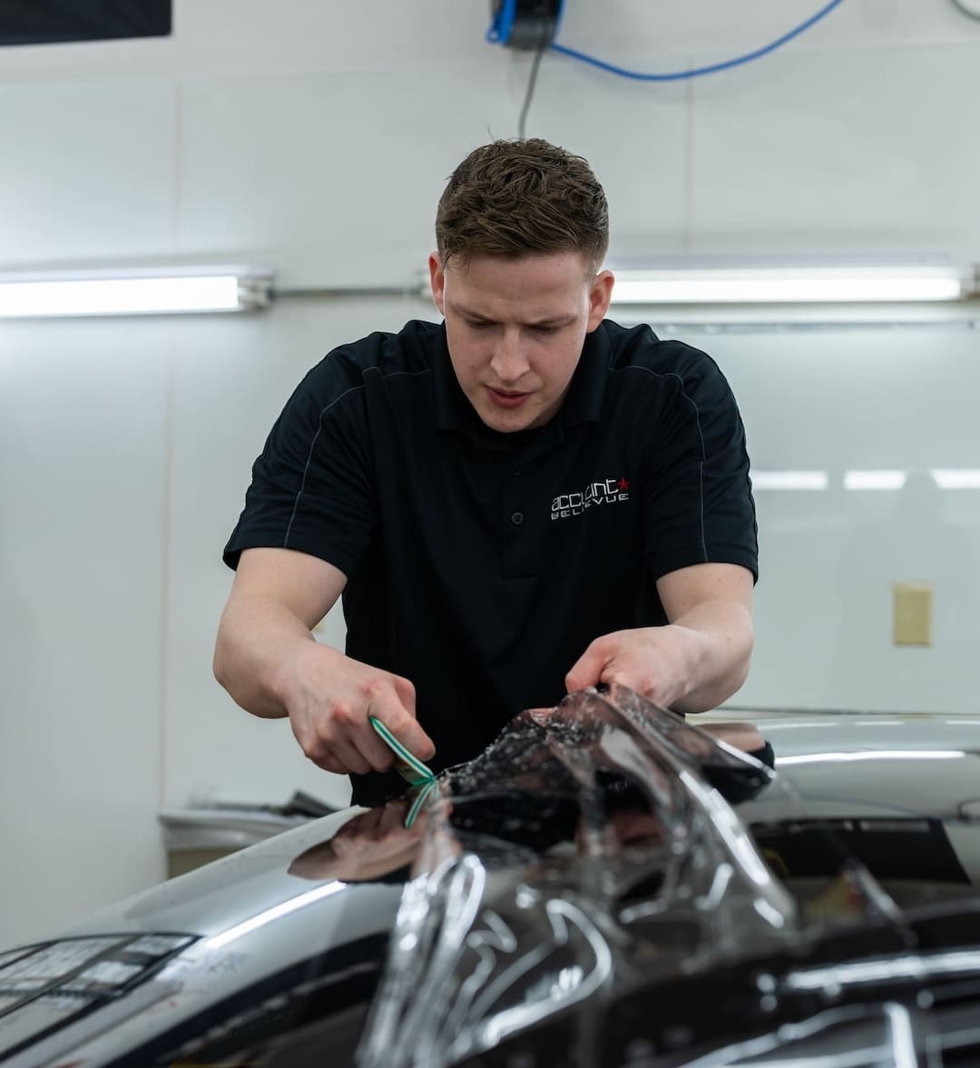 Person Trimming Window Tint To Fit A Car's Windshield