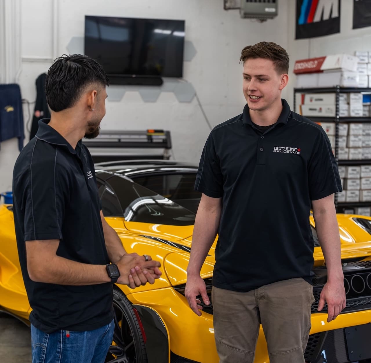 Two auto mechanics discussing in front of a yellow sports car