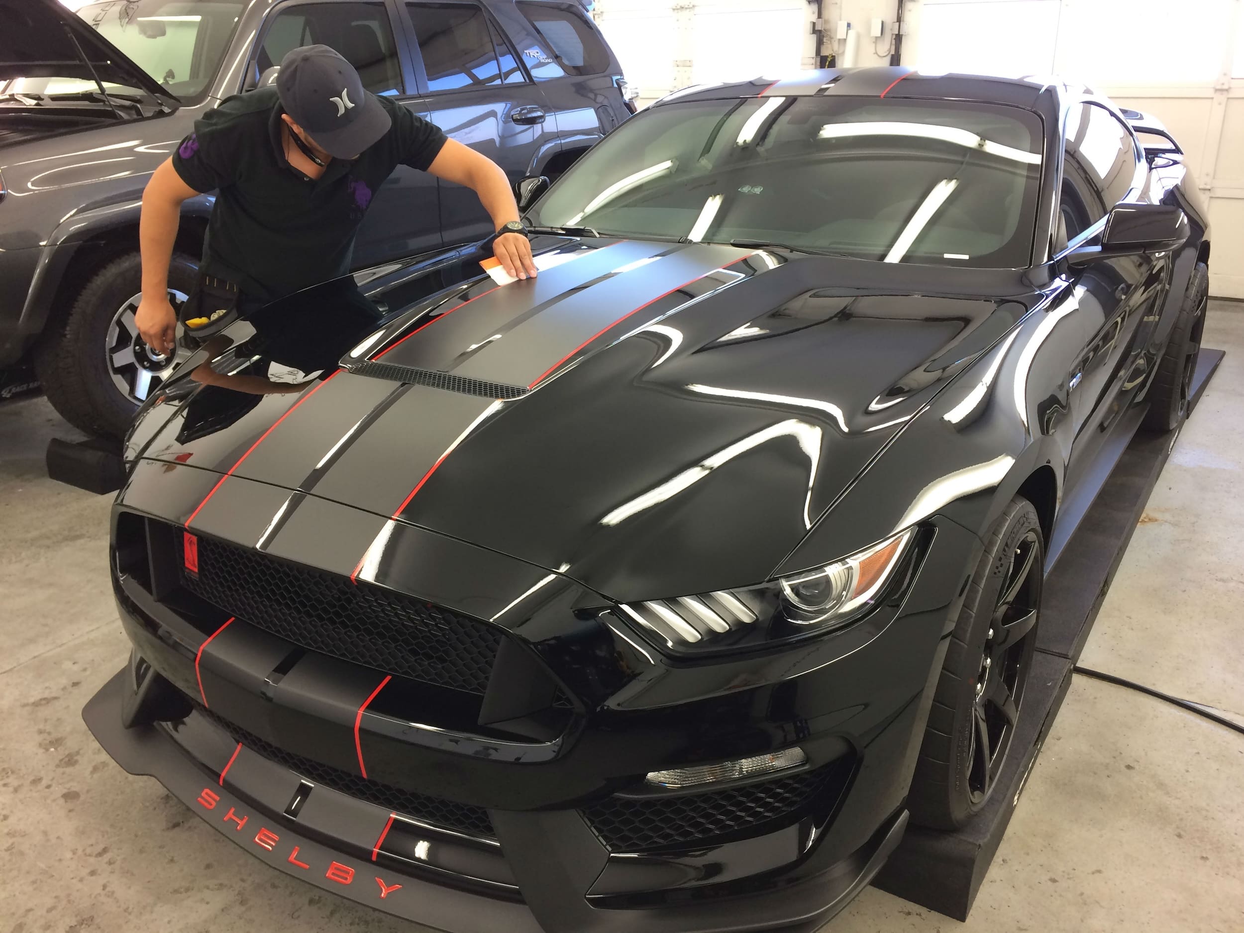 Man inspects vinyl accent racing stripes on black Shelby GT