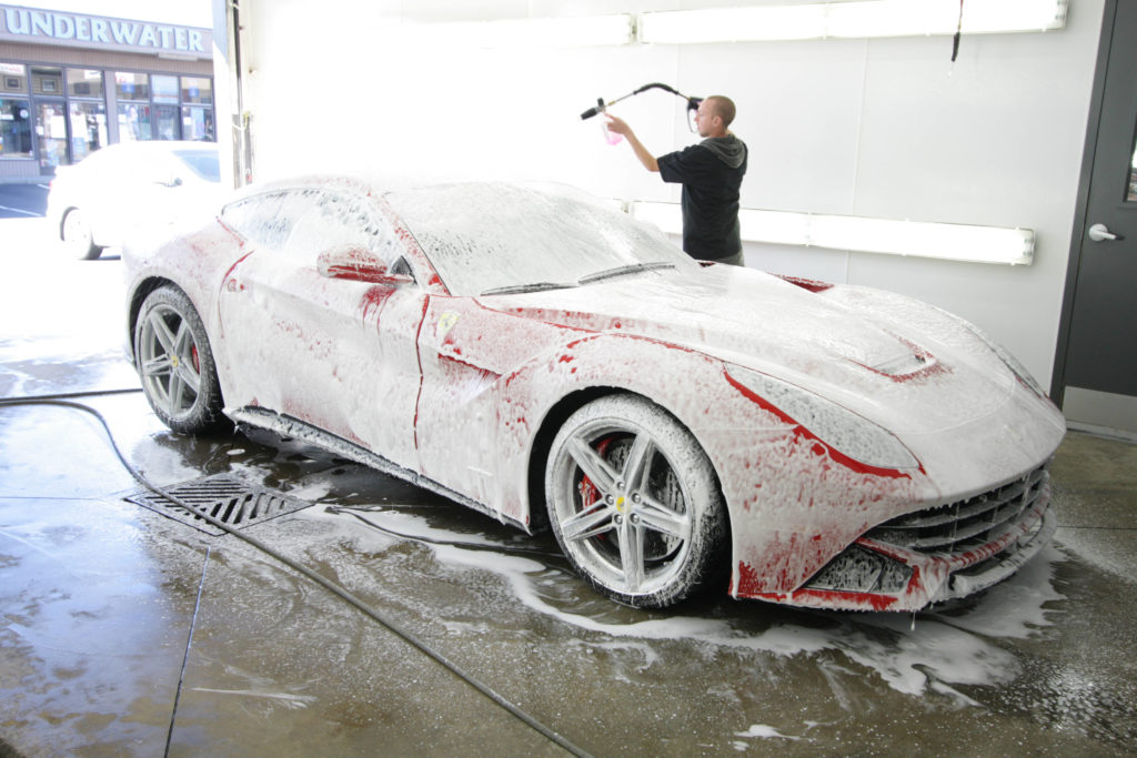 Person washing car with soap and power washer