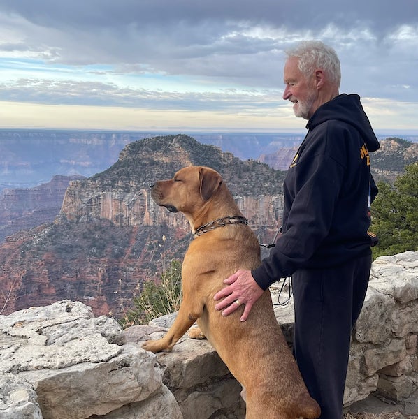 J. DeBruler and Booker, his dog, looking over a rock barrier at the mountains beyond